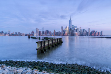 Fototapeta premium View on Financial District from Hudson River Pier during sunrise with long exposure