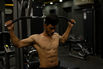 Fototapeta na wymiar An young and handsome Indian Bengali brunette man with muscular body doing exercise in a multi gym. Fitness and Indian lifestyle.