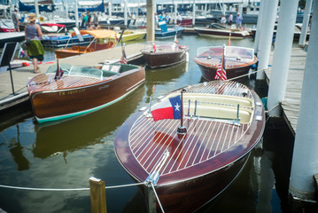 Vintage wooden motorboats moored along a pier with Texas flag