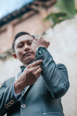 Selective focus of groom is standing with concrete wall background. Wedding concept.
