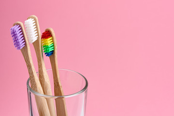 Three bamboo toothbrush close-up in glass on pink background. Eco friendly and zero waste concept photo.