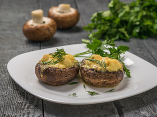 Two mushrooms stuffed with cheese and chicken breast on a white plate.
