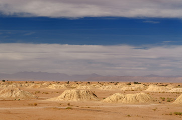 Fototapeta na wymiar Many earth mound Khettara wells in the Tafilalt plain with High Atlas mountains Morocco