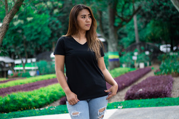 Fototapeta premium Young woman wearing black t shirt posing at park in front view, suitable for mock up template, background, etc.