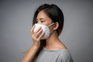 Young woman wearing surgical mask, studio shot