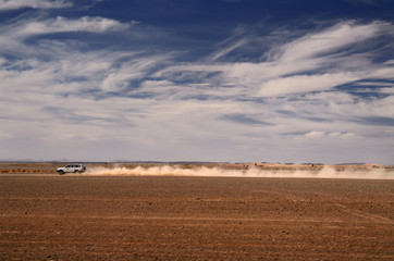 Dust trail of 4x4 car speeding from Erfoud to the Erg Chebbi desert Morocco © Reimar