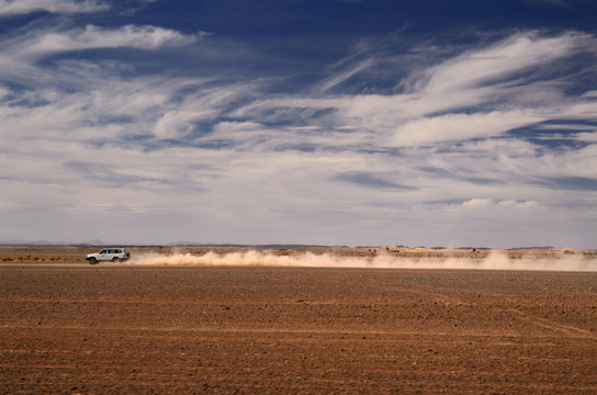 Dust trail of 4x4 car speeding from Erfoud to the Erg Chebbi desert Morocco