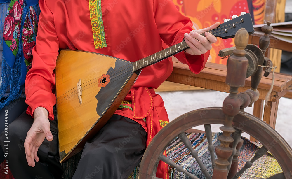 Wall mural the musician plays a Russian folk musical instrument, a balalaika, in an ancient national costume