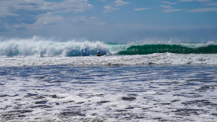 Beautiful aerial view of surfers surfing in Naranjo Beach 
