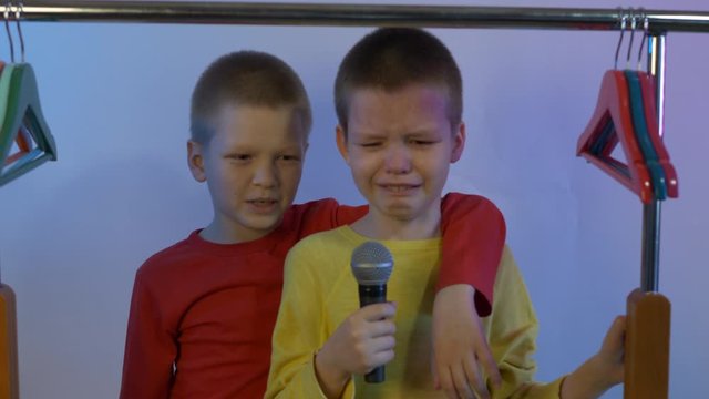 Two happy little boys received latest smartphone models as gift from their parents. children turned on music and sang karaoke in front of microphone on stand. Brothers are happy together, adore gadget