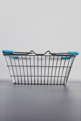 minimalistic shopping, empty shopping basket on reflective grey surface with white background behind it