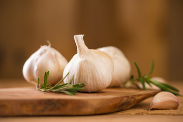 Garlic with rosemary and thyme and spices on a wooden background