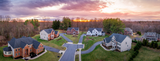 Aerial sunset panorama of brick facade luxury mansion type single family homes neighborhood cul-de-sac street American real estate in a new construction in Maryland USA with dramatic sky - obrazy, fototapety, plakaty