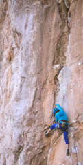 A woman in a helmet climbs a beautiful orange rock.