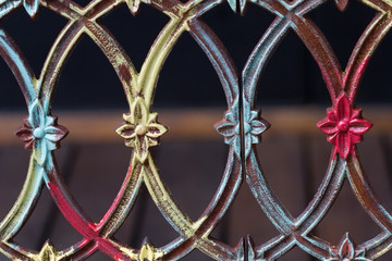 An old multicolored iron fence with flowery symbols.