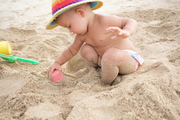 Adorable toddler girl playing with beach toys on white sand beach