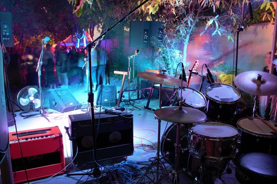 Behind The Back Line At A Gig. Drums, Guitar And Amps Behind Microphones Front Row.