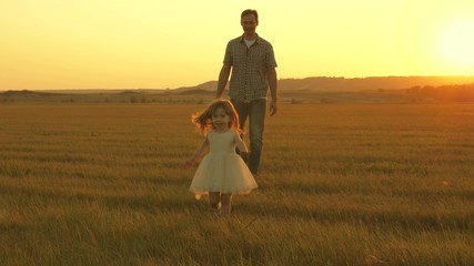 Dad and baby in park. happy childhood concept. Little daughter walks with dad in meadow. child plays in meadow with his father. child runs on the grass. family walks in evening out of town.