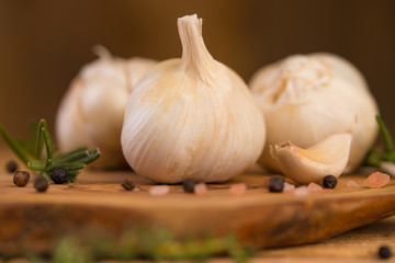 Spicy fresh garlic with rosemary and thyme and black pepper. Culinary splash, on a wooden background.