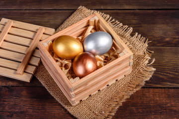 Fototapeta na wymiar Easter eggs in gift wooden box on dark wooden background