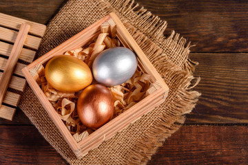 Easter eggs in gift wooden box on dark wooden background