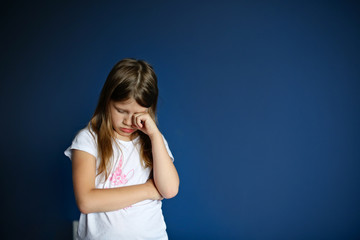 child girl sad, offended, crying on deep blue