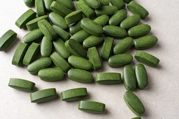 green pills chlorella on a gray background. nutritional supplements for a healthy diet
