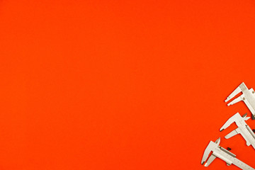 On a bright orange background, measuring tool calipers, copyspace