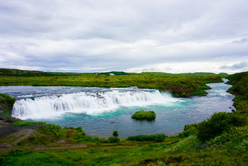 beautiful small waterfall with azure water in Iceland in cloudy weather
