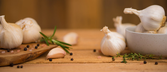 Garlic banner, background. Spices, Bulbs of garlic on a wooden rustic table in the shape of a panorama. A bunch of garlic peeled cloves