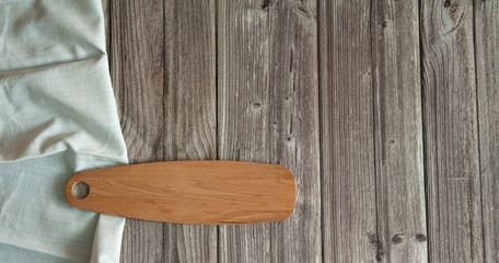 Cutting and serving Board made of beech wood and white linen napkin on a brown wooden background. Free space. Copy space.