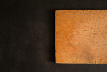 The kitchen composition. Old cutting board made of birch wood close-up on a dark concrete background. Free space. Copy space.