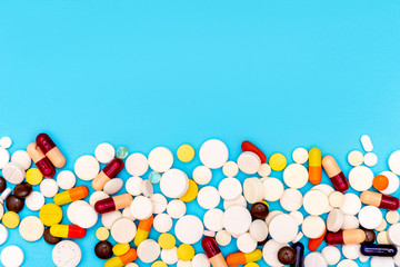 Different pills on blue background, top view and space for text