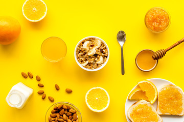 Granola for healthy breakfast. Still life composition with fruits and toast on yellow background top-down