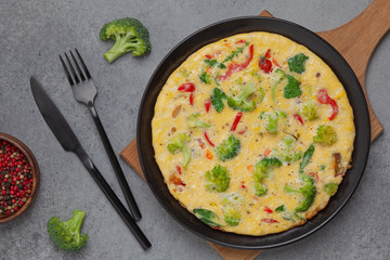 Frittata with fresh vegetables. Omelette with broccoli, paprika, tomato and herbs. Top view. 