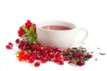 Parts of a pomegranate with pomegranate seeds and leaves, flowers, dry tea of carcade and full cup of tea isolated on white background