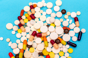 Various pills on a blue background, top view close up
