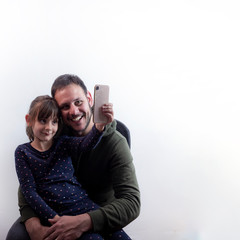 father and daughter of caucasian origin, having their photo taken with a smartphone, on a white background, lifestyle concept