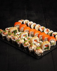 Traditional Japanese sushi food rolls on a black wooden background