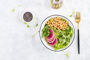 Trendy salad. Vegan Buddha bowl with chickpeas, watermelon radish, cucumber and peas sprouts. Healthy balanced eating. Top view, overhead, flat lay