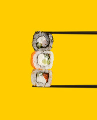 Japanese sushi rolls are sandwiched with wooden sticks. Yellow background .Creative minimalist concept