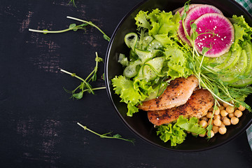 Trendy salad. Buddha bowl dish with chicken fillet, chickpea, cucumber, radish,  fresh lettuce salad, pea sprouts  and chia seeds. Healthy food. Top view, overhead, copy space