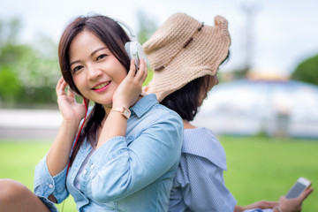 Young carefree attractive Asian women enjoy to listening music in garden, happiness and cheerful friendship concept.	