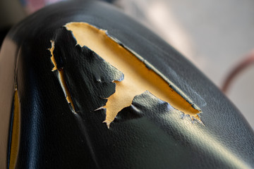 Old Leather seat. Broken Leather. Closeup of old black leather motorcycle seat damage.