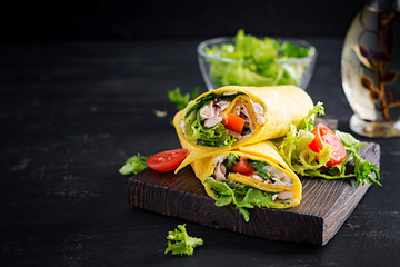 Fresh tortilla wraps with chicken and fresh vegetables on wooden board. Chicken burrito. Mexican cuisine. Copy space