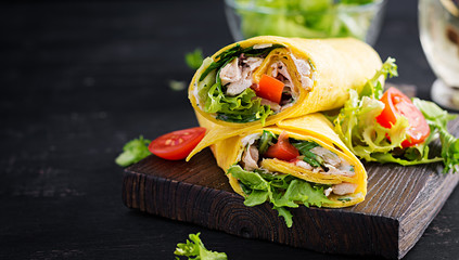 Fresh tortilla wraps with chicken and fresh vegetables on wooden board. Chicken burrito. Mexican cuisine. Copy space