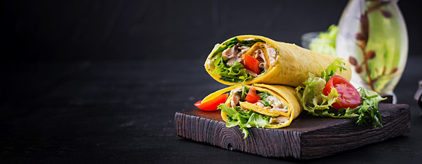 Fresh tortilla wraps with chicken and fresh vegetables on wooden board. Chicken burrito. Mexican cuisine. Banner