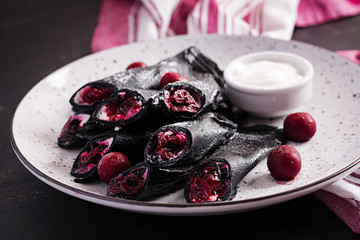 Sweet pancakes with ricotta and cherries. Black pancakes. Breakfast.