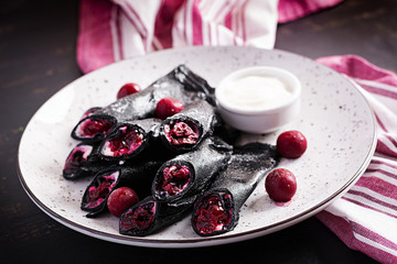 Sweet pancakes with ricotta and cherries. Black pancakes. Breakfast.