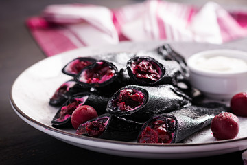 Sweet pancakes with ricotta and cherries. Black pancakes. Breakfast.